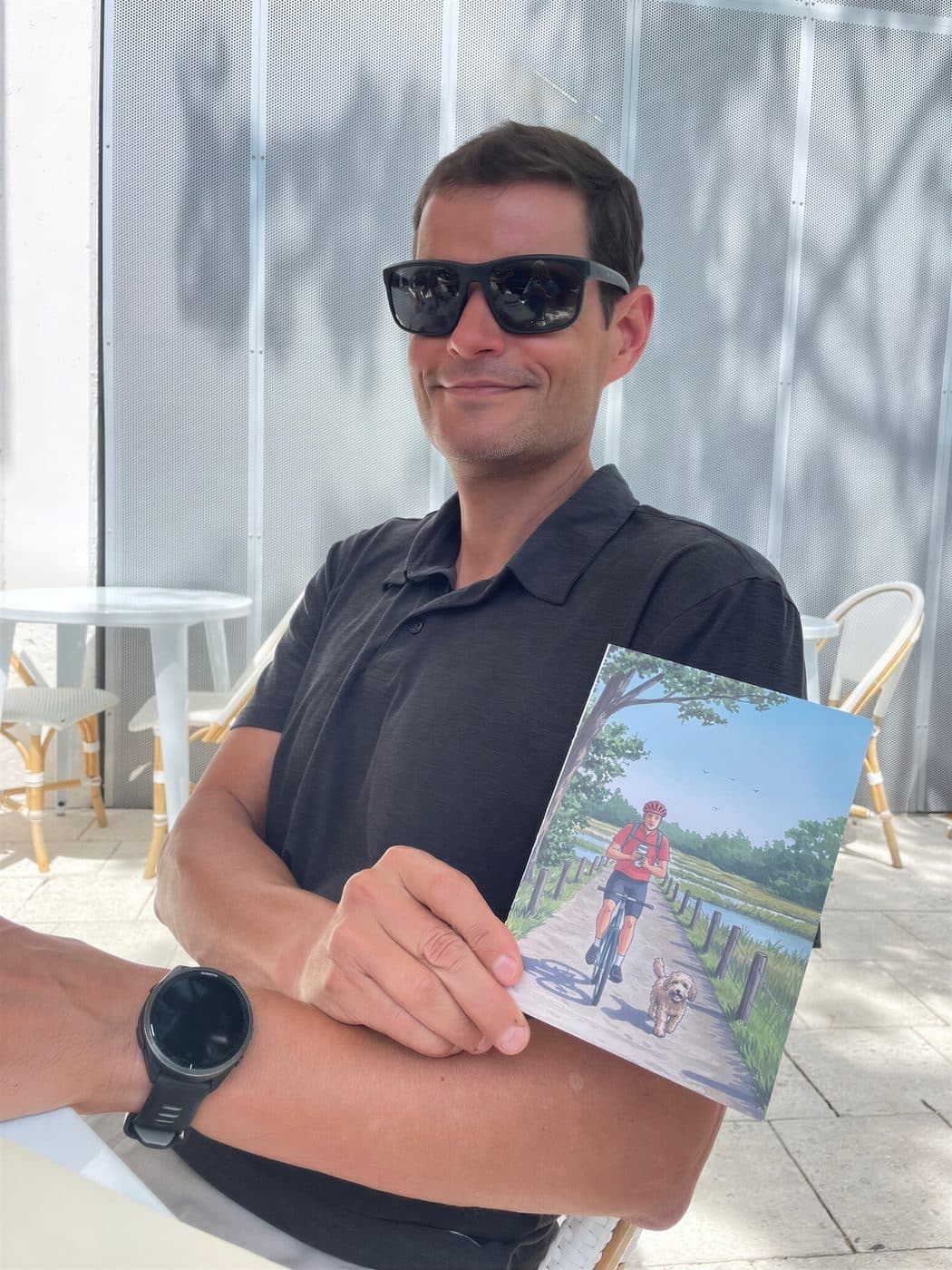 A man holding a card illustrated as him cycling with his dog